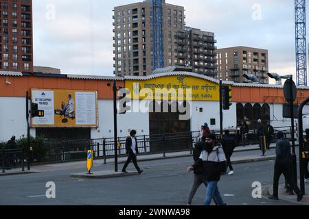 Männer überqueren die Straße vor einem großen Sikh Gurdwara in Southall, einem Gebiet im Westen Londons mit einer großen ethnischen Sikh-Bevölkerung Stockfoto