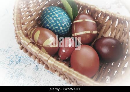 Ostereier in verschiedenen Farben, gefärbt mit Zwiebelschalen und Farbe in Korb. Gemüsemuster auf der Schale. Traditionelle festliche Farben Stockfoto