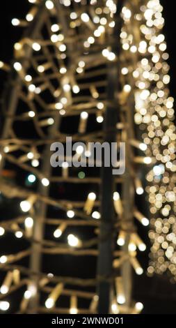 Straßengirlanden mit weißen kleinen Lampen am Abend auf einer Stadtstraße. Festliche Neujahrsdekoration Stadtstraßen und Parks Stockfoto