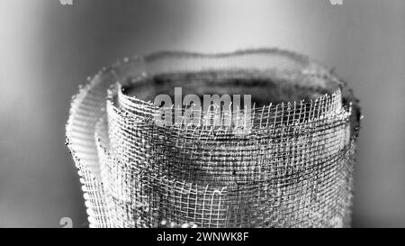 Metallgitter. Gerolltes Netz in Grau. Robustes Stahl- oder Aluminiumgitter mit ausgefransten Kanten. Stockfoto