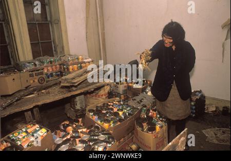 Horten, die das tägliche Leben nicht bewältigen können. Francis Parfitt im heruntergekommenen Spargrove Manor House, Batcombe, Somerset. 1988 1980er Jahre Großbritannien. Das mit einem Wassergraben versehene Manor House wurde von den zurückgezogen lebenden Parfitt-Schwestern besetzt, die in Armut lebten, während sie noch versuchten, ihre Farm zu erhalten. Man sieht sie hier mit leeren Dosen Katzenfutter und einigen ungeöffneten Dosen. Das Herrenhaus war seit über 200 Jahren in ihrer Familie. HOMER SYKES Stockfoto