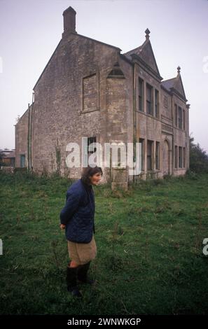 Francis Parfitt vor dem Spargrove Manor House, fütterte gerade die Tiere, die sie bewirtschaften. Spargrove Manor House, Batcombe, Somerset. 1988 1980er Jahre Großbritannien. Das heruntergekommene, mit Wassergraben versehene Manor House wurde von den zurückgezogen lebenden Schwestern der Familie Parfitt besetzt, die in Armut lebten, während sie noch versuchten, ihre Farm zu erhalten. Das Herrenhaus war seit über 200 Jahren in ihrer Familie. HOMER SYKES Stockfoto