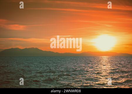 Meereslandschaft mit Bergen am Horizont bei Sonnenuntergang. Rockies am Abend. Blick auf den Olymp am Horizont. Wunderschöne Natur Griechenlands Stockfoto