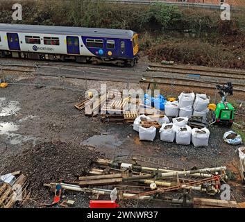 Ein nördlicher Zug passiert alte Semaphore-Signale, die vom Bahnübergang der Chapel Lane entfernt wurden und auf dem Hof an der Appley Bridge liegen, die nun verschrottet werden Stockfoto