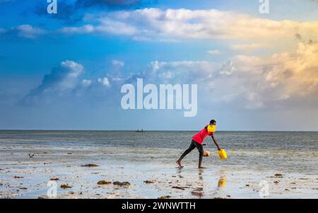 Ein Fischer mit gelben Plastikbehältern am Strand, Jambiani, Sansibar, Tansania Stockfoto