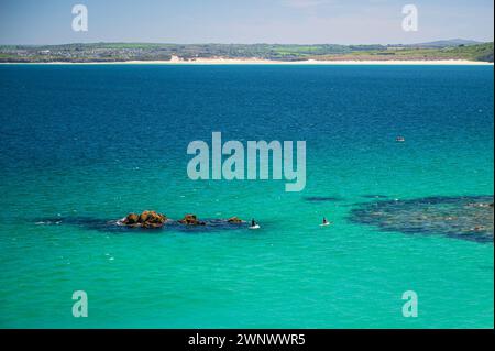 Zwei Paddleboarder, im klaren blauen Meer vor der Küste von St. Ives, Cornwall, England, an einem klaren Sommertag Stockfoto
