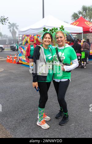 Zwei Frauen in grünen T-Shirts posieren eng zusammen auf der 18. Jahresstraße Patrick's Day 5 km Walk & Run, Pharr, Hidalgo, Texas, USA. Stockfoto