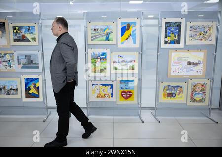 Kiew, Ukraine. März 2024. Ein Mitarbeiter des Kernkraftwerks spaziert in der Nähe von Kinderzeichnungen über die Besetzung des Kernkraftwerks Zaporischzhia bei einer Veranstaltung, die dem Gedenken an den zweiten Jahrestag der Besetzung des Kernkraftwerks Zaporischzhia durch die russischen Streitkräfte in Kiew gewidmet ist. Das Kernkraftwerk Zaporischschschhya wurde am 4. März 2022 von russischen Truppen besetzt. (Foto: Oleksii Chumachenko/SOPA Images/SIPA USA) Credit: SIPA USA/Alamy Live News Stockfoto