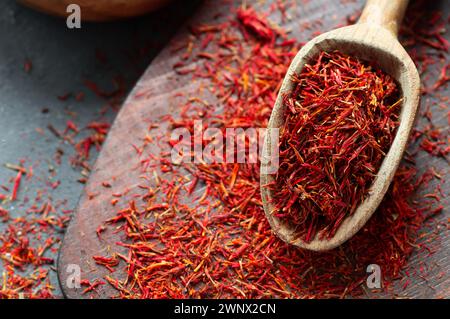 Haufen getrockneter Safranwürze im Löffel auf rustikalem Hintergrund, Gewürze und Kräuter Konzept (Crocus sativus) Stockfoto