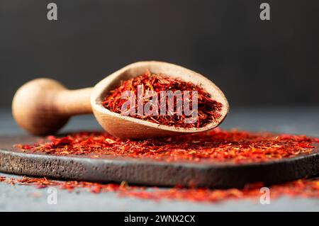 Haufen getrockneter Safranwürze im Löffel auf rustikalem Hintergrund, Gewürze und Kräuter Konzept (Crocus sativus) Stockfoto