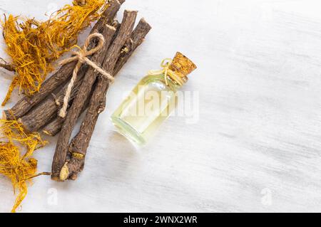 Glasflasche Süßholzwurzel ätherisches Öl mit Lakritzfaser auf rustikalem Hintergrund ( glycyrrhiza glabra ) Stockfoto