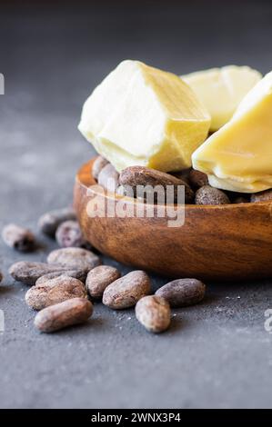 Kakaobutter oder Kakaobohnenfestes Öl und rohe Kakaobohnen auf rustikalem Hintergrund, gesundes natürliches Öl Stockfoto