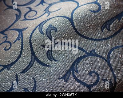 Seidenblauer Stoff mit goldenen Locken. Textilien für Polster, Vorhänge und festliche Kleidung. Der Stoff ist sanft in Wellen gefaltet. Stockfoto