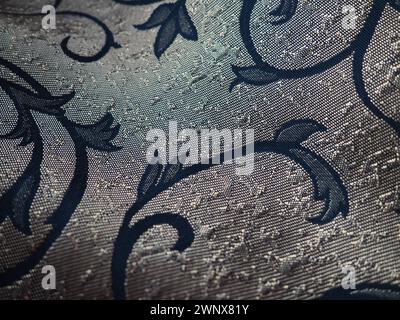 Seidenblauer Stoff mit goldenen Locken. Textilien für Polster, Vorhänge und festliche Kleidung. Der Stoff ist sanft in Wellen gefaltet. Stockfoto