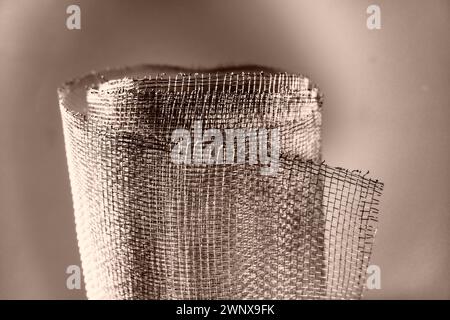 Metallgitter. Gerolltes Netz in Grau. Robustes Stahl- oder Aluminiumgitter mit ausgefransten Kanten. Stockfoto