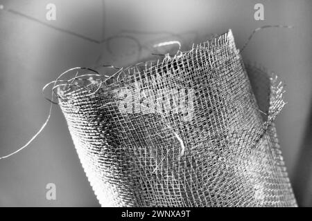 Metallgitter. Gerolltes Netz in Grau. Robustes Stahl- oder Aluminiumgitter mit ausgefransten Kanten. Stockfoto