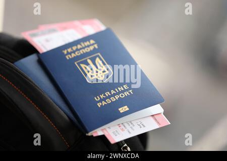 Zwei ukrainische biometrische Pässe mit Flugtickets auf schwarzem touristischem Rucksack Nahaufnahme Stockfoto