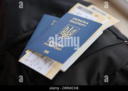 Zwei ukrainische biometrische Pässe mit Flugtickets auf schwarzem touristischem Rucksack Nahaufnahme Stockfoto