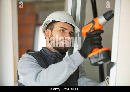Ernsthafter junger Baumeister mit Akku-Bohrmaschine Stockfoto