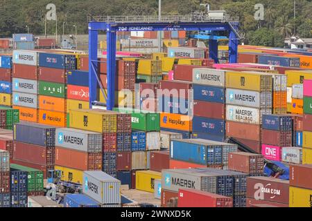 Puerto Quetzal, Guatemala - 19. Januar 2024: Im Hafen der Stadt gestapelte Schiffscontainer mit einem Containerkran im Hintergrund Stockfoto