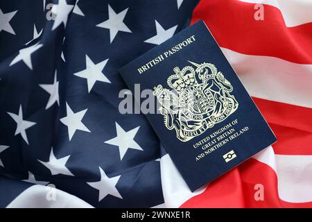 Blauer britischer Pass auf dem Hintergrund der US-Nationalflagge aus nächster Nähe. Tourismus und Diplomatie Stockfoto
