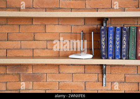 Regal mit Büchern und wlan-Router an einer Ziegelwand Stockfoto