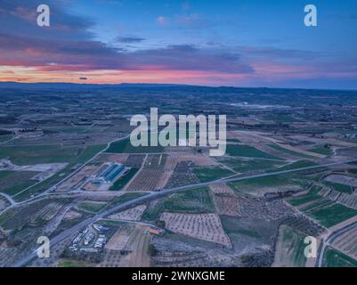 Luftaufnahme der Stadt Arbeca und ihrer ländlichen Umgebung bei rötlichem Sonnenaufgang (Les Garrigues, Lleida, Katalonien, Spanien) Stockfoto