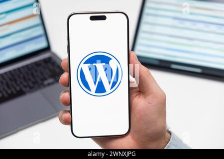 PRAG, TSCHECHISCHE REPUBLIK - 21. JANUAR 2024: WordPress-Logo auf dem Bildschirm des Mobiltelefons in der Hand des Menschen auf dem Hintergrund des Arbeitsplatzes. Stockfoto