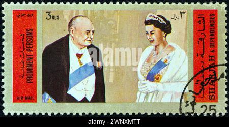 SHARJAH – UM 1972: Eine in den Vereinigten Arabischen Emiraten gedruckte Briefmarke zeigt Winston Churchill und Königin Elisabeth II. Von England Stockfoto