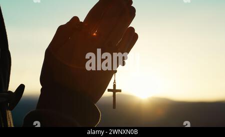Der Mann betet bei Sonnenuntergang mit Rosenkranz Stockfoto