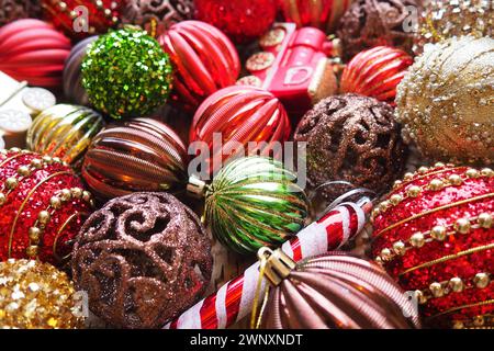 Weihnachtskugeln und Dekorationen zum Neujahr sind ganz nah. Viel Dekor in Gold, Rot, Gelb, Braun, Grün, Silber. Gestreifte Weihnachtskugeln liegen in einem Haufen Stockfoto