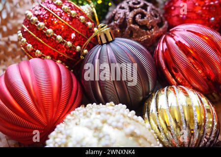 Weihnachtskugeln und Dekorationen zum Neujahr sind ganz nah. Viel Dekor in Gold, Rot, Gelb, Braun, Grün, Silber. Gestreifte Weihnachtskugeln liegen in einem Haufen Stockfoto