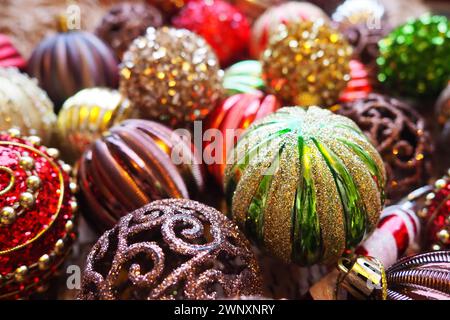 Weihnachtskugeln und Dekorationen zum Neujahr sind ganz nah. Viel Dekor in Gold, Rot, Gelb, Braun, Grün, Silber. Gestreifte Weihnachtskugeln liegen in einem Haufen Stockfoto