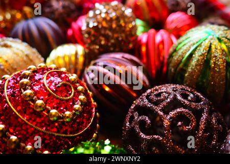 Weihnachtskugeln und Dekorationen zum Neujahr sind ganz nah. Viel Dekor in Gold, Rot, Gelb, Braun, Grün, Silber. Gestreifte Weihnachtskugeln liegen in einem Haufen Stockfoto