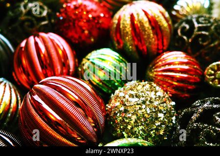 Weihnachtskugeln und Dekorationen zum Neujahr sind ganz nah. Viel Dekor in Gold, Rot, Gelb, Braun, Grün, Silber. Gestreifte Weihnachtskugeln liegen in einem Haufen Stockfoto