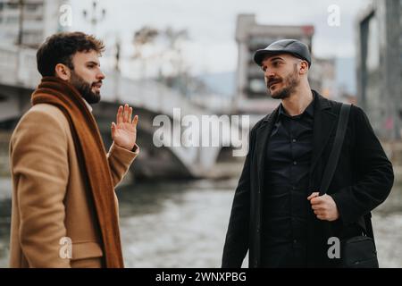 Eine fokussierte Außenaufnahme, bei der zwei Männer in professioneller Kleidung gefangen werden, die in einer Stadt mit einem Brückenhintergrund ernsthaft diskutiert werden. Stockfoto