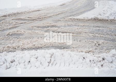 Eine Gabel oder ein Anschlussgleis von einem Kreisverkehr. Schnee am Straßenrand. Schlechtes Wetter und Verkehr. Schnee auf dem Asphalt. Schwierige Fahrbedingungen Stockfoto