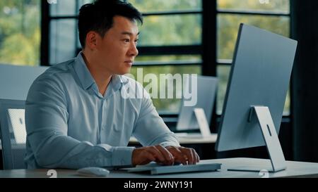 Konzentrierter reifer asiatischer japanischer koreanischer Mann Büroangestellter professioneller Geschäftsmann Unternehmer Arbeit in der Geschäftsfirma Computerspiel entwickeln Stockfoto