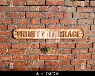 Straßenschild der Trinity Terrace auf einer alten Backsteinmauer in der Stadt Weymouth, Dorset, England. Stockfoto