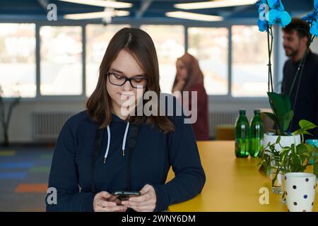 Porträt einer glücklichen multiethnischen Geschäftsfrau mit Smartphone in der Agentur. Erfolgreiche Geschäftsfrau in legerer Kleidung arbeitet in Coworking Creative Stockfoto
