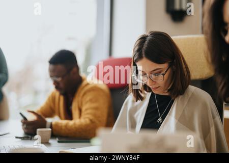 Fokussierte, multiethnische Mitarbeiter, die an Laptops arbeiten und Papierkram in einer modernen Büroumgebung erledigen. Stockfoto