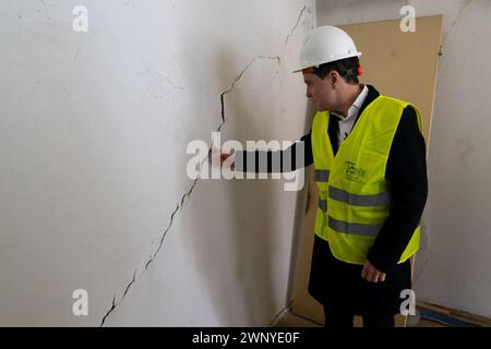 Bukarest, Rumänien - 4. März 2024: Nicusor Dan, der Bürgermeister von Bukarest, betrachtet einen tiefen Riss in einer Mauer während des Besuchs eines Mehrfamilienwohnblocks, der in den 50er Jahren in der Baltagului Straße Nr. gebaut wurde 17, Sektor 5, in dem das Rathaus der Hauptstadt mit der Konsolidierung beginnt, mit Mitteln aus dem PNRR-PNRR der nationalen Wiederaufbauungs- und Resilienzpläne. Die Widerstandsstruktur des Gebäudes ist stark betroffen und wird von der Stadtverwaltung für die Konsolidierung von Gebäuden mit seismischer Gefährdung konsolidiert und saniert. Quelle: Lucian Alecu/Alamy Live Stockfoto