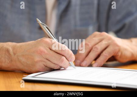Senior-Mann unterschreibt letztes Testament und Testament am Holztisch, Nahaufnahme Stockfoto
