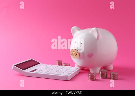 Finanzielle Einsparungen. Schweinebank, Münzen und Taschenrechner auf rosafarbenem Hintergrund Stockfoto