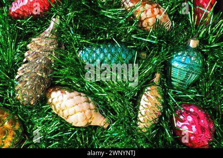Mehrfarbige Glaskegel auf grünem Weihnachtsbaum Lametta. Schöne Weihnachtsspielzeuge und Dekorationen als Hintergrund. Rot, gelb, grün und rosa glänzend Stockfoto