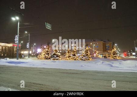 Petrosawodsk, Karelien, Russland, 01.13.2024: Gagarin-Platz, Blick auf die Leninallee, Weihnachtsbäume. Winterabend oder -Nacht, Schnee weht in der Nähe der Straße Stockfoto