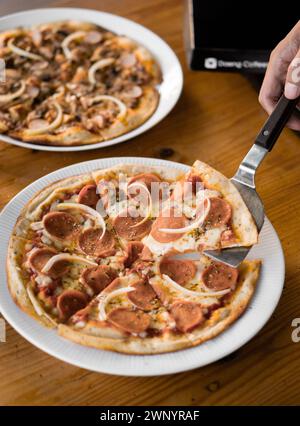 Zwei ganze Pizzen, serviert auf einem weißen Teller Stockfoto
