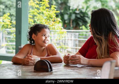 Nahaufnahme eines brünetten Latina-Mädchens, das mit ihrer Mutter spricht, während er morgens Kaffee trinkt. Stockfoto