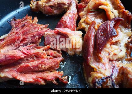 Geröstetes geräuchertes Schweinefleisch, Schulter oder Knie. Köstliches Fleisch auf einem schwarzen Backblech mit Tropfen Pflanzenöl, aus dem Ofen genommen. Schweinefleisch Delikatesse für Stockfoto