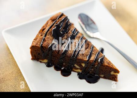 Süßes, zartes dreieckiges Stück Schokoladen-Nuss-Kuchen, mit flüssiger Schokolade gefüllt, auf Teller serviert Stockfoto